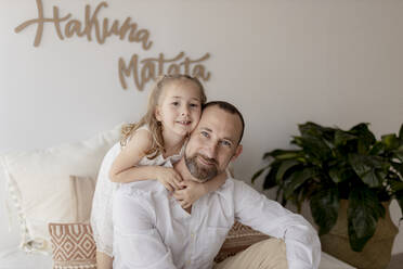 Porträt eines glücklichen Vaters, der mit seiner Tochter zu Hause Kopf an Kopf liegt - GMLF00145