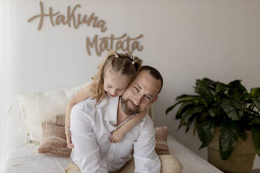 Porträt eines glücklichen Vaters und seiner kleinen Tochter, die zu Hause kuscheln - GMLF00147