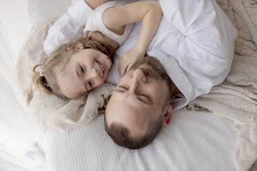 Father and little daughter resting together on bed - GMLF00149