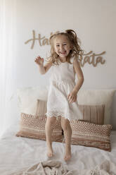 Porträt eines glücklichen kleinen Mädchens, das auf dem Bett springt - GMLF00163