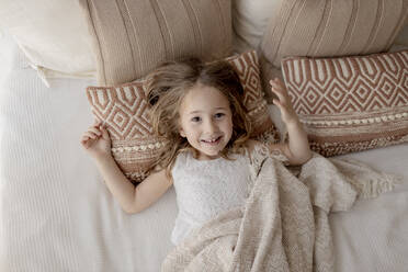 Porträt eines glücklichen kleinen Mädchens auf dem Bett liegend - GMLF00166