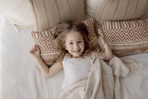 Portrait of happy little girl lying on bed - GMLF00166