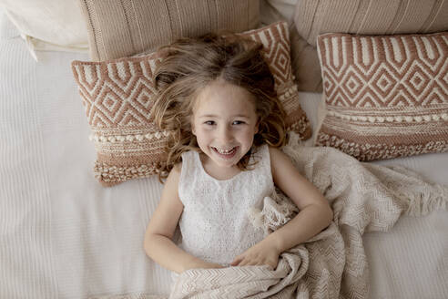 Porträt eines lachenden kleinen Mädchens auf dem Bett liegend - GMLF00167