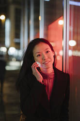 Junge Frau am Telefon in der Stadt bei Nacht - AHSF02380