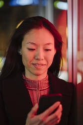 Junge Frau benutzt Smartphone in der nächtlichen Stadt - AHSF02381