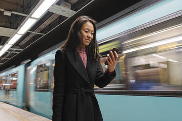 Young woman using smartphone in metro station - AHSF02406