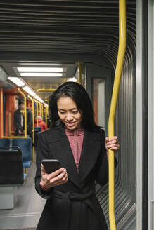 Junge Frau benutzt Smartphone in einer U-Bahn - AHSF02408