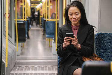 Junge Frau benutzt Smartphone in einer U-Bahn - AHSF02424