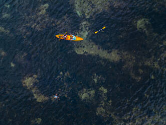 Indonesien, Bali, Sanur, Luftaufnahme von zwei Kajakfahrern, die an einem Mann vorbeifahren, der im seichten Wasser fischt - KNTF04575