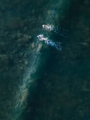 Indonesien, Bali, Seminyak, Luftaufnahme von Surfern im grünen Meerwasser - KNTF04578