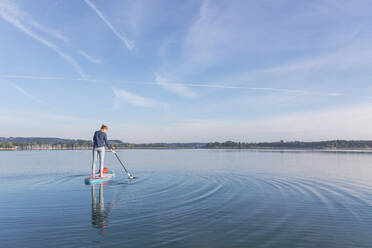 Frau, die am Morgen auf einem See auf einem Surfbrett steht, Deutschland - MMAF01302