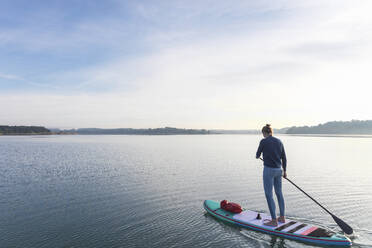 Frau, die am Morgen auf einem See auf einem Surfbrett steht - MMAF01304