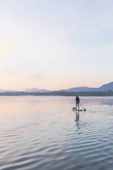 Frau, die am Morgen auf einem See auf einem Surfbrett steht, Deutschland - MMAF01311