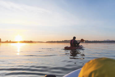 Frau, die am Morgen auf einem See auf einem Surfbrett steht, Deutschland - MMAF01318