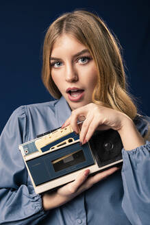 Blond woman with cassette player in front of blue background - AGGF00060