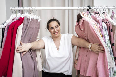 Seamstress between clothes in tailor shop - VPIF02382