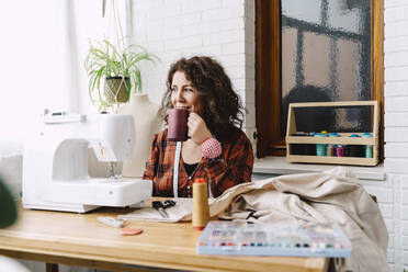 Woman sewing at home having a coffee break - ERRF03544