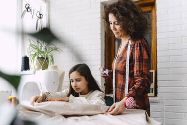 Mother and daughter sewing at home - ERRF03566