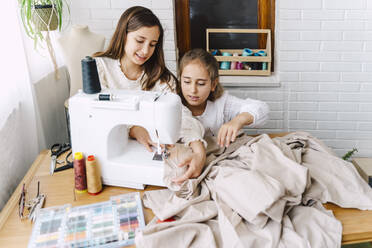 Two girls sewing at home - ERRF03570