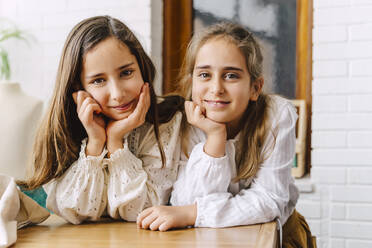 Portrait of two girls leaning on table at home - ERRF03573