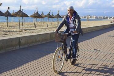 Man riding a bike at beach promenade during winter - ECPF00888