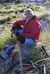 Lächelnder Mountainbiker schaut in die Kamera während der Pause - ECPF00893