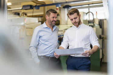 Zwei Männer besprechen einen Plan in einer Fabrik - DIGF09996