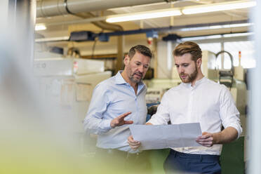 Zwei Männer besprechen einen Plan in einer Fabrik - DIGF09997