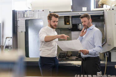 Zwei Männer besprechen einen Plan in einer Fabrik - DIGF10002