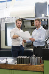 Zwei Männer besprechen einen Plan in einer Fabrik - DIGF10003