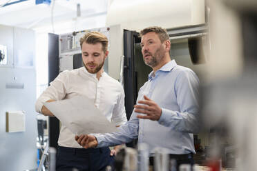 Zwei Männer besprechen einen Plan in einer Fabrik - DIGF10004