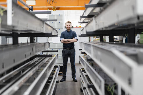 Porträt eines lächelnden jungen Mannes in einer Fabrik - DIGF10018