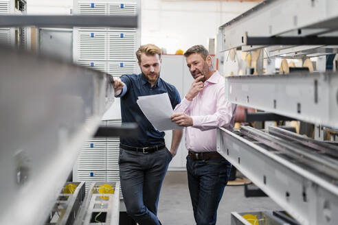 Zwei Männer besprechen einen Plan in einer Fabrik - DIGF10027