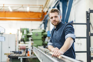 Porträt eines selbstbewussten jungen Mannes in einer Fabrik - DIGF10040