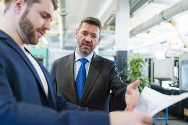 Two businessmen having a work meeting in a factory discussing a plan - DIGF10061