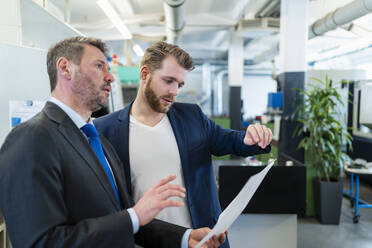 Two businessmen having a work meeting in a factory discussing a plan - DIGF10064