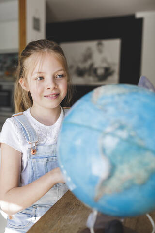 Porträt eines lächelnden Mädchens mit Blick auf einen Globus, lizenzfreies Stockfoto