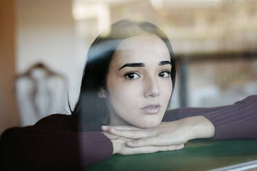 Porträt einer jungen Frau hinter einer Fensterscheibe - TCEF00535