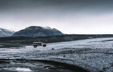 Mini van amidst dramatic landscape in Jokulsarlon, Iceland - DAMF00430