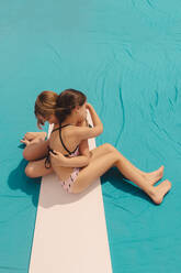 Two girls in swimwear hugging each other - ERRF03599