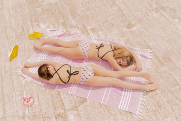 Zwei Mädchen in Badeanzügen liegen auf einer Decke und entspannen sich - ERRF03621
