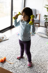 Porträt eines kleinen Mädchens, das mit stummen Glocken zu Hause übt - VABF02847