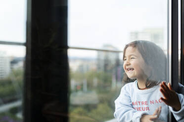 Porträt eines glücklichen kleinen Mädchens auf dem Balkon mit Blick in die Ferne - VABF02852