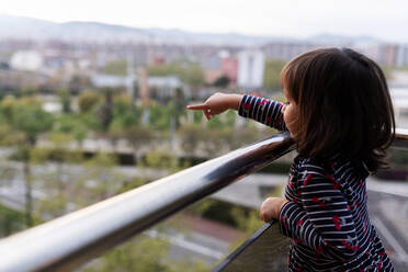 Kleines Mädchen steht auf einem Balkon und zeigt auf etwas - VABF02870