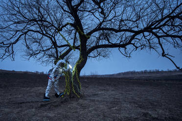 Spacewoman discovering a tree in the evening - VPIF02391