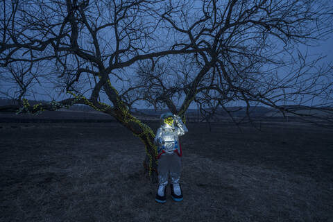 Spacewoman discovering a tree in the evening stock photo