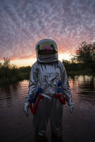 Portrait of spacewoman standing in water at sunset stock photo