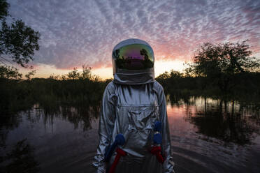 Porträt einer im Wasser stehenden Raumfahrerin bei Sonnenuntergang - VPIF02403