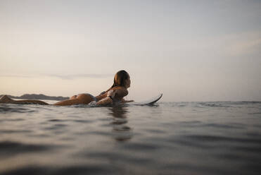 Weibliche Surferin auf dem Surfbrett liegend, Costa Rica - HWHF00007