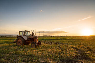 Roter Traktor auf goldenem Sonnenuntergangshimmel. - CAVF80519